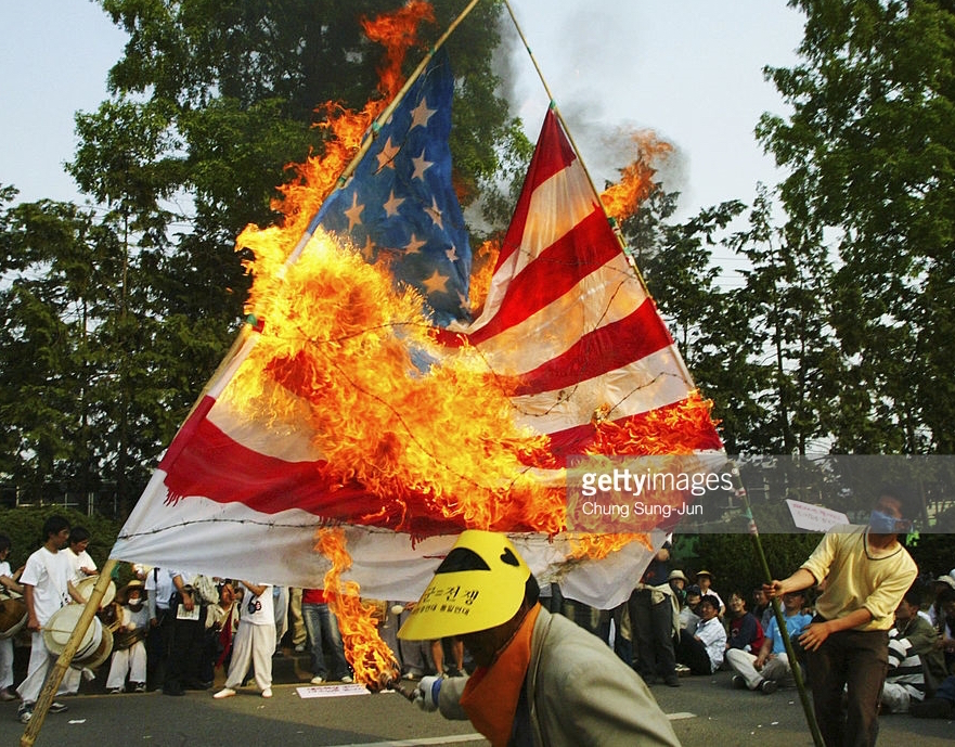 GWANGJU, SOUTH KOREA - MAY 15: South Korean protesters burn a U.S. flag during an anti-American demonstration near a South Korean Air Force base May 15, 2005 in Gwangju, South Korea. The protesters were objecting to the deployment of the U.S. Patriot anti-missile system at the air force base and demanded the withdrawal of all U.S. troops from the Korean peninsula. (Photo by Chung Sung-Jun/Getty Images)